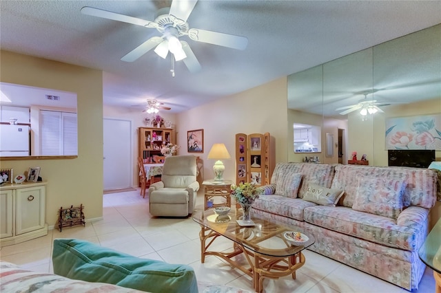 living room featuring ceiling fan, a textured ceiling, and light tile floors