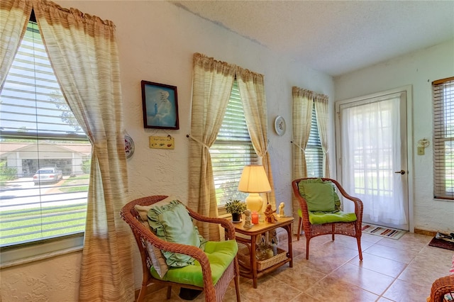 living area featuring a healthy amount of sunlight, a textured ceiling, and tile floors