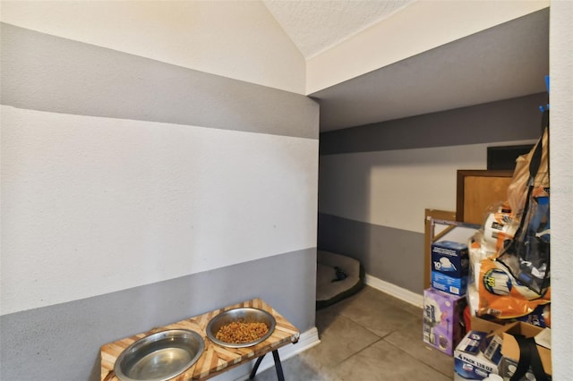 interior space featuring a textured ceiling, tile patterned flooring, and lofted ceiling