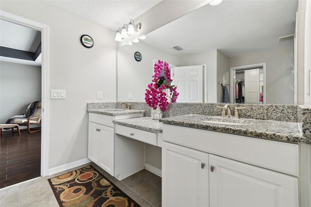 full bath with visible vents, a textured ceiling, vanity, baseboards, and tile patterned floors