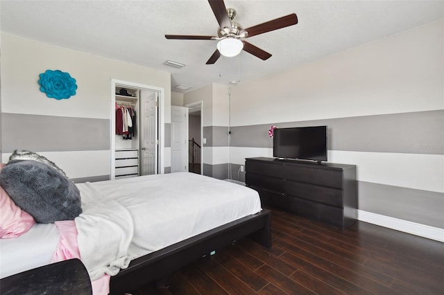 bedroom with ceiling fan, wood finished floors, visible vents, baseboards, and a closet