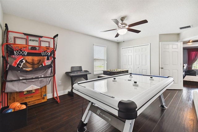 rec room featuring dark wood-type flooring, visible vents, ceiling fan, and baseboards