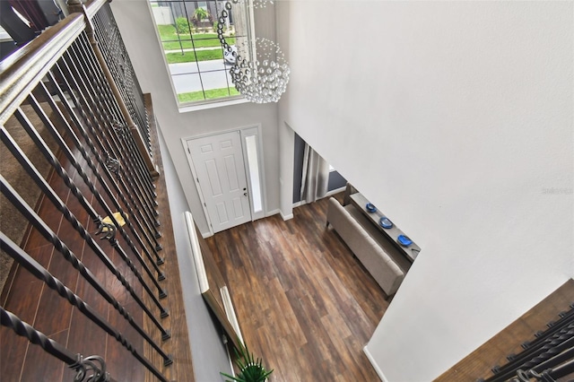 foyer featuring an inviting chandelier, a high ceiling, baseboards, and wood finished floors