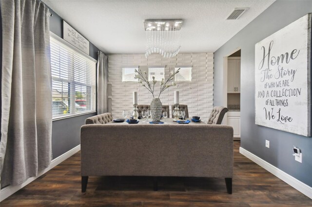 dining area with dark wood-type flooring, a textured ceiling, and a notable chandelier