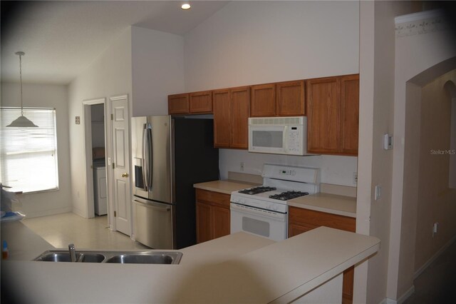 kitchen featuring lofted ceiling, white appliances, sink, hanging light fixtures, and washer / clothes dryer