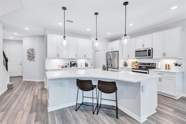 kitchen featuring white cabinets, a large island, stainless steel appliances, and decorative light fixtures