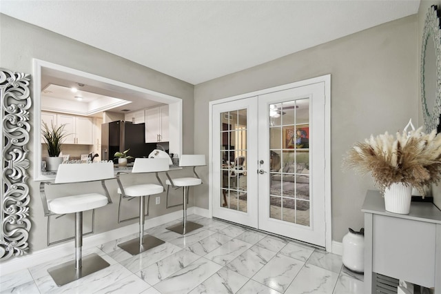 interior space featuring a tray ceiling and french doors