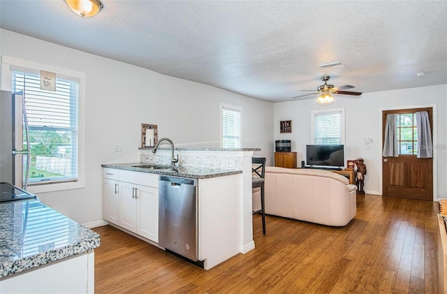 kitchen featuring light stone countertops, white cabinetry, sink, stainless steel appliances, and light hardwood / wood-style flooring