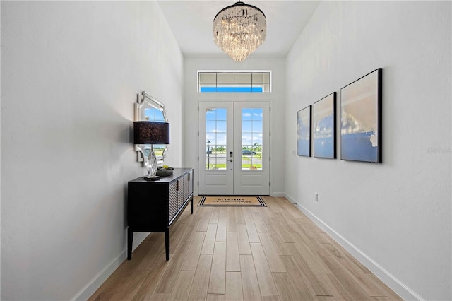 interior space with french doors, light hardwood / wood-style floors, and an inviting chandelier