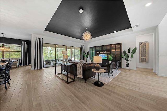 living room with plenty of natural light, a raised ceiling, and a chandelier