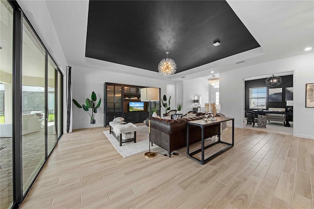 living room featuring a tray ceiling and an inviting chandelier