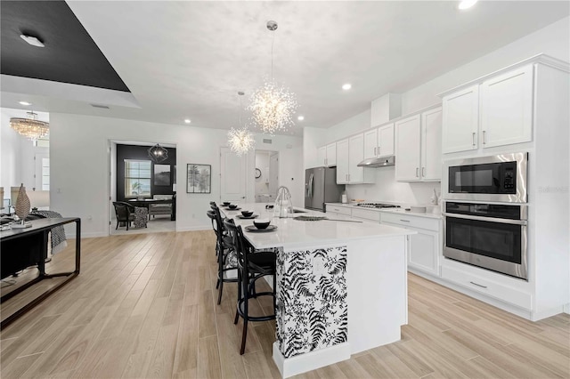 kitchen with a chandelier, appliances with stainless steel finishes, white cabinetry, and pendant lighting