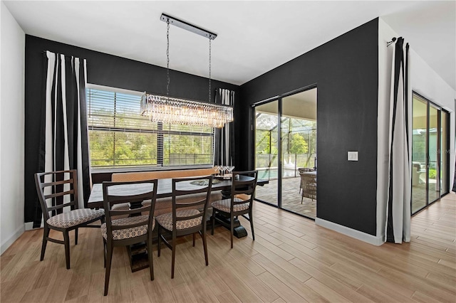 dining space with light wood-type flooring and an inviting chandelier