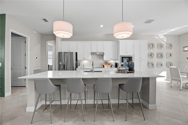 kitchen featuring white cabinets, stainless steel fridge, hanging light fixtures, and sink