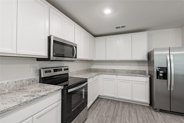 kitchen featuring appliances with stainless steel finishes, light hardwood / wood-style flooring, and white cabinetry