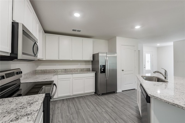 kitchen with sink, light hardwood / wood-style flooring, light stone countertops, appliances with stainless steel finishes, and white cabinetry