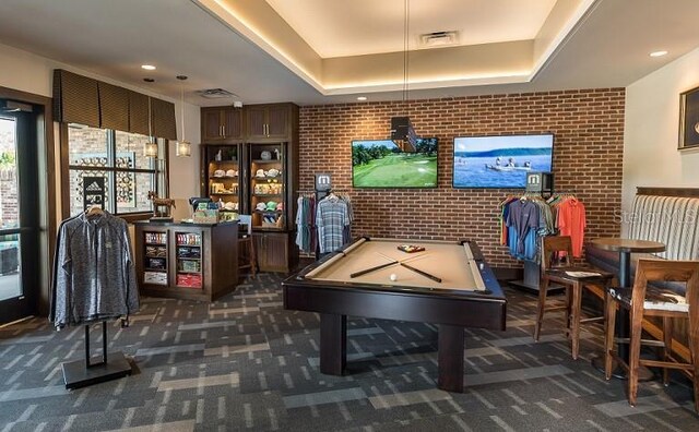 playroom featuring dark colored carpet, a tray ceiling, pool table, and brick wall