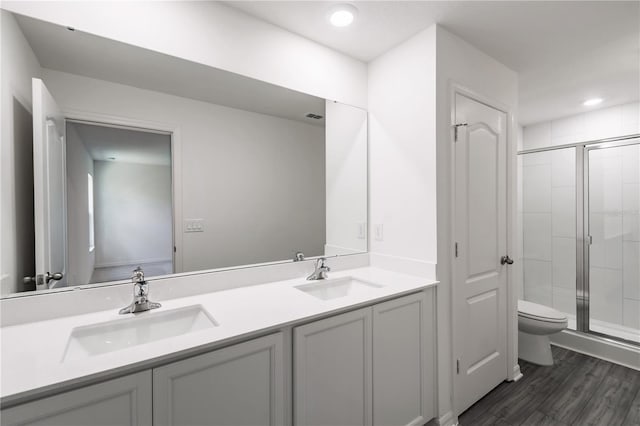 bathroom with hardwood / wood-style floors, vanity, a shower with door, and toilet