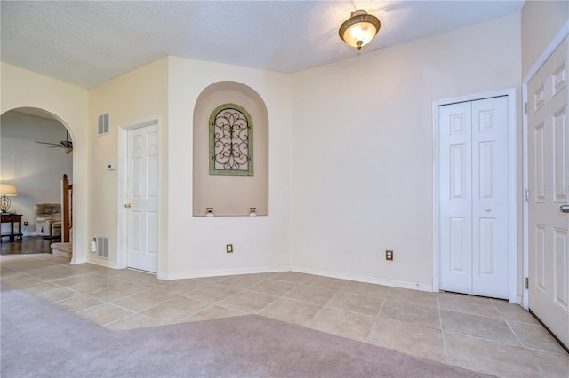 tiled empty room with a textured ceiling and ceiling fan