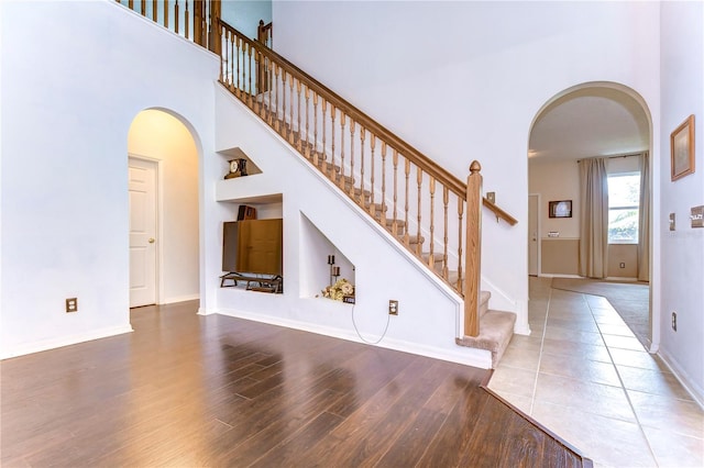 stairs with hardwood / wood-style flooring and a towering ceiling