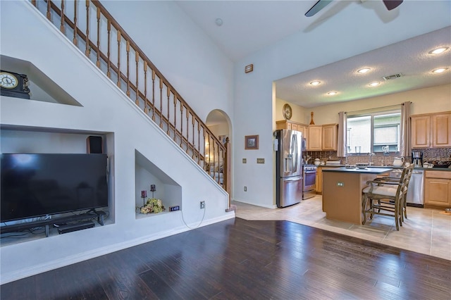 kitchen with a center island, backsplash, a kitchen bar, appliances with stainless steel finishes, and light wood-type flooring