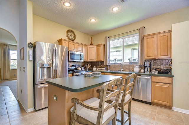 kitchen featuring a center island, light tile patterned floors, sink, and appliances with stainless steel finishes