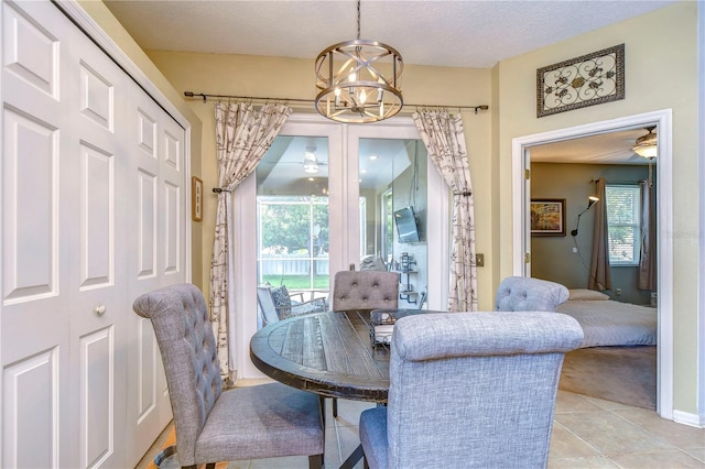 tiled dining space featuring a textured ceiling and ceiling fan with notable chandelier