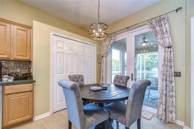 tiled dining area featuring ceiling fan with notable chandelier