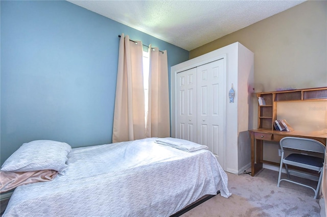 bedroom featuring a closet, light colored carpet, and a textured ceiling