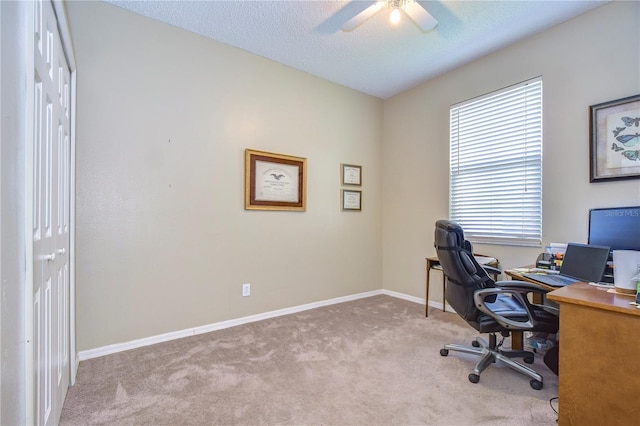 carpeted home office with ceiling fan and a textured ceiling