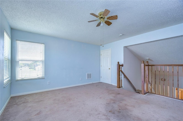 carpeted spare room with a textured ceiling and ceiling fan