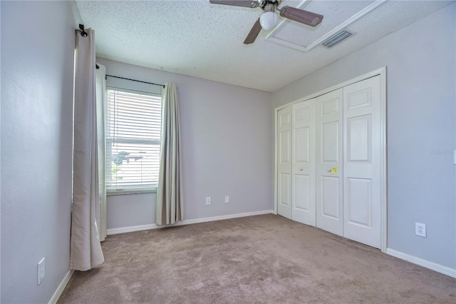 unfurnished bedroom featuring a textured ceiling, ceiling fan, light carpet, and a closet