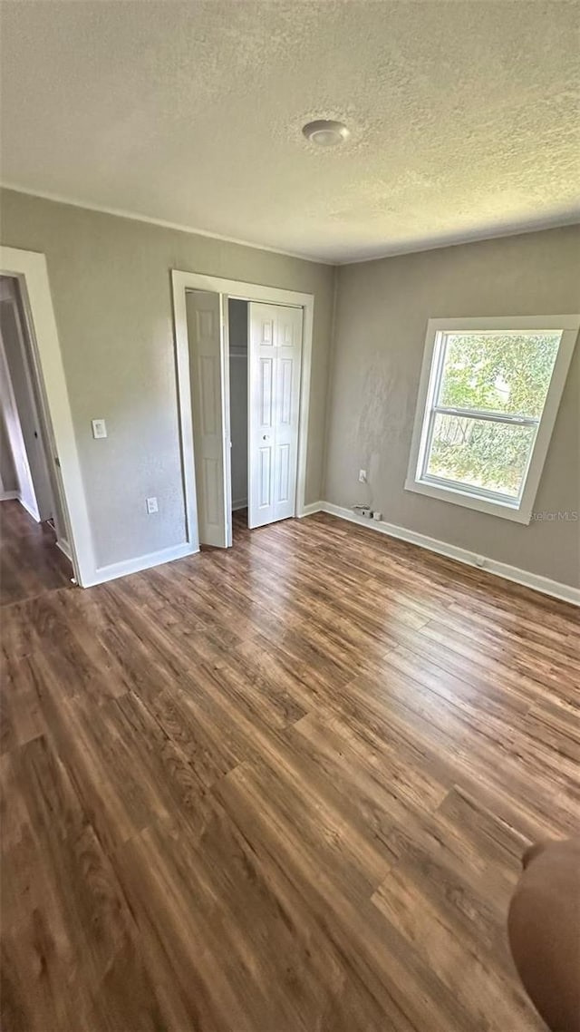 unfurnished bedroom featuring dark wood-type flooring and a textured ceiling