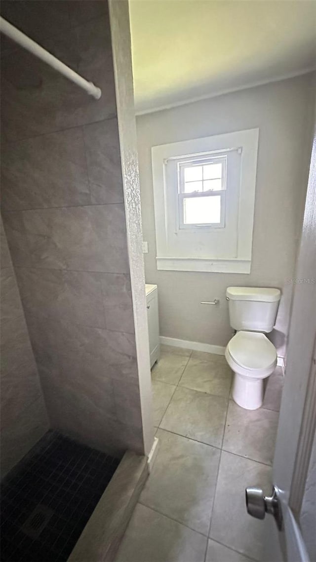 bathroom with tile patterned floors, toilet, and tiled shower