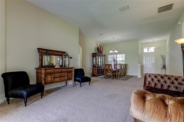 living room featuring a high ceiling, light colored carpet, and a notable chandelier