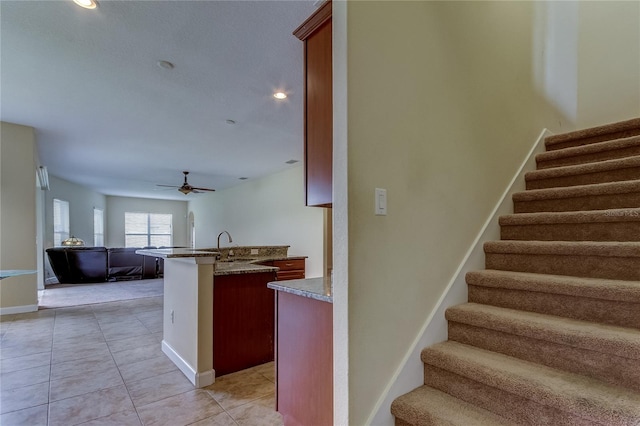 staircase with tile patterned floors, ceiling fan, and sink