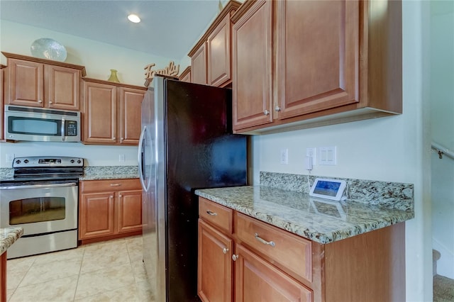 kitchen featuring light stone countertops, light tile patterned floors, and appliances with stainless steel finishes