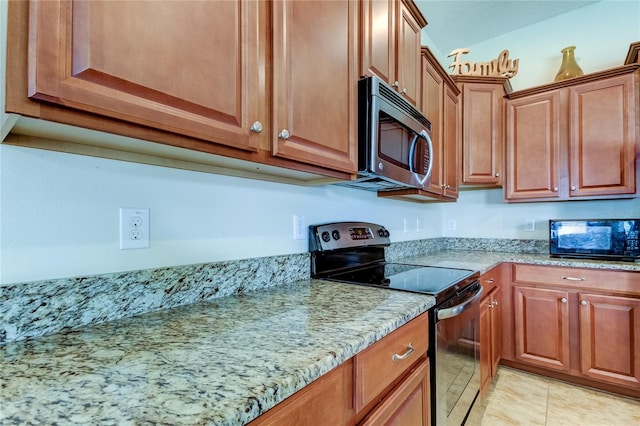 kitchen featuring light tile patterned floors, stainless steel appliances, and light stone counters