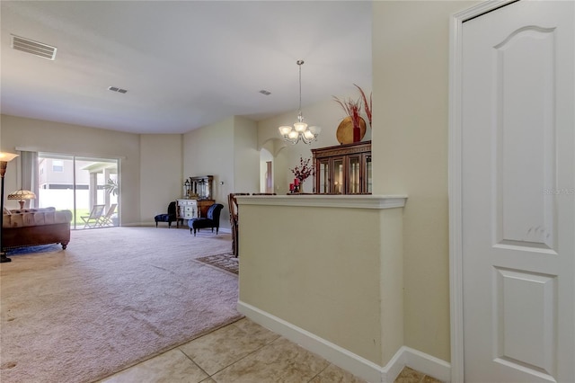 hallway with light carpet and an inviting chandelier