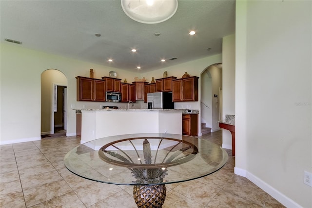 kitchen with a kitchen island with sink and appliances with stainless steel finishes