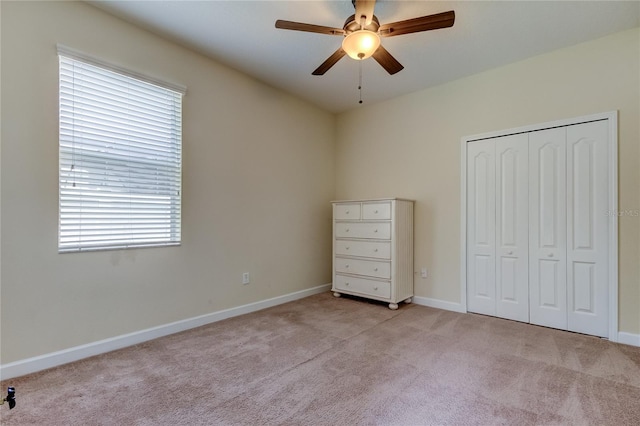 unfurnished bedroom featuring a closet, ceiling fan, and light colored carpet