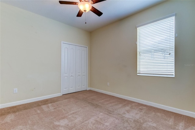 unfurnished bedroom featuring ceiling fan, a closet, and light colored carpet