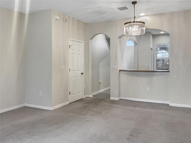 carpeted empty room featuring a notable chandelier