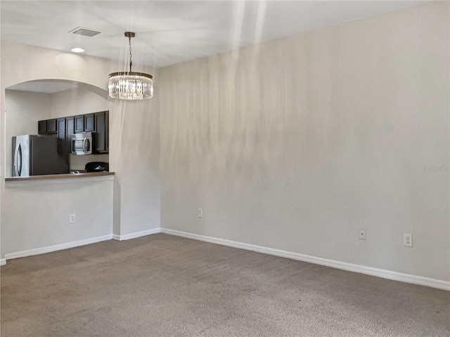 carpeted spare room with a chandelier