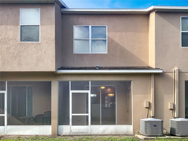 back of property with a sunroom and central AC