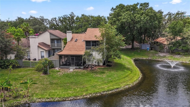 rear view of property with a lawn, a sunroom, a water view, and a balcony