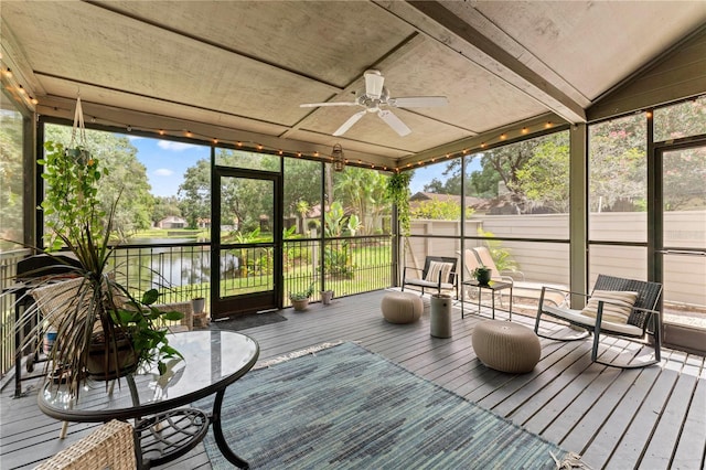 unfurnished sunroom featuring ceiling fan, a water view, and lofted ceiling