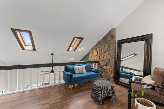 living area with ceiling fan, vaulted ceiling with skylight, and wood-type flooring