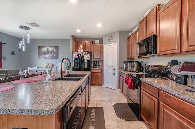 kitchen featuring sink, decorative light fixtures, light tile patterned floors, an island with sink, and black appliances