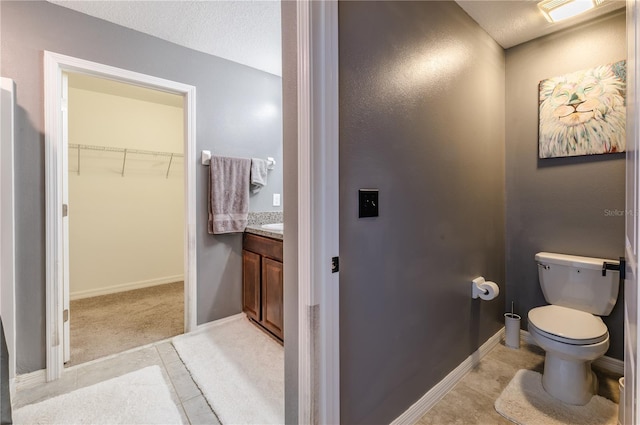 bathroom featuring tile patterned flooring, vanity, a textured ceiling, and toilet